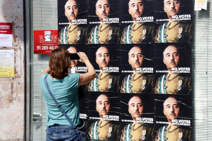 Una dona fa una fotografia a una paret farcida de cartells amb la cara de Franco, al barri de Llefià de Badalona / Jordi Pujolar