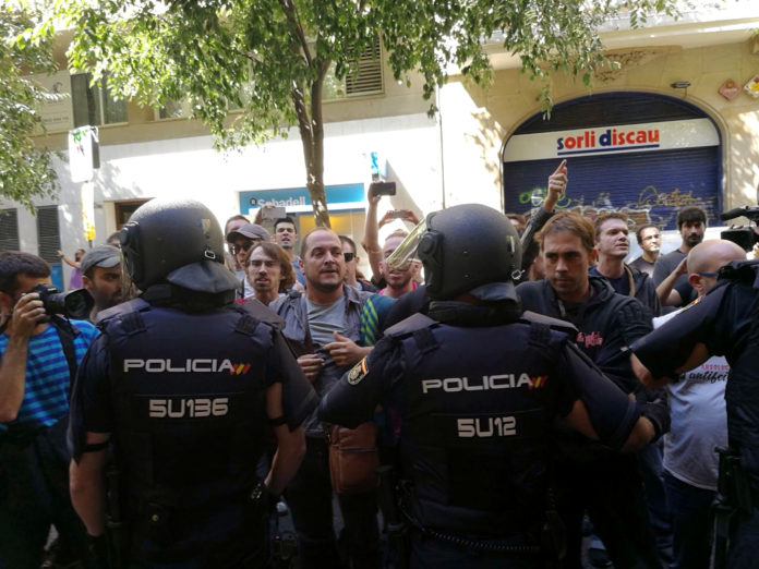 La policia espanyola envoltant la seu de la CUP, mentre simpatitzants criden en contra de l'actuació i en favor de l'1-O / CUP
