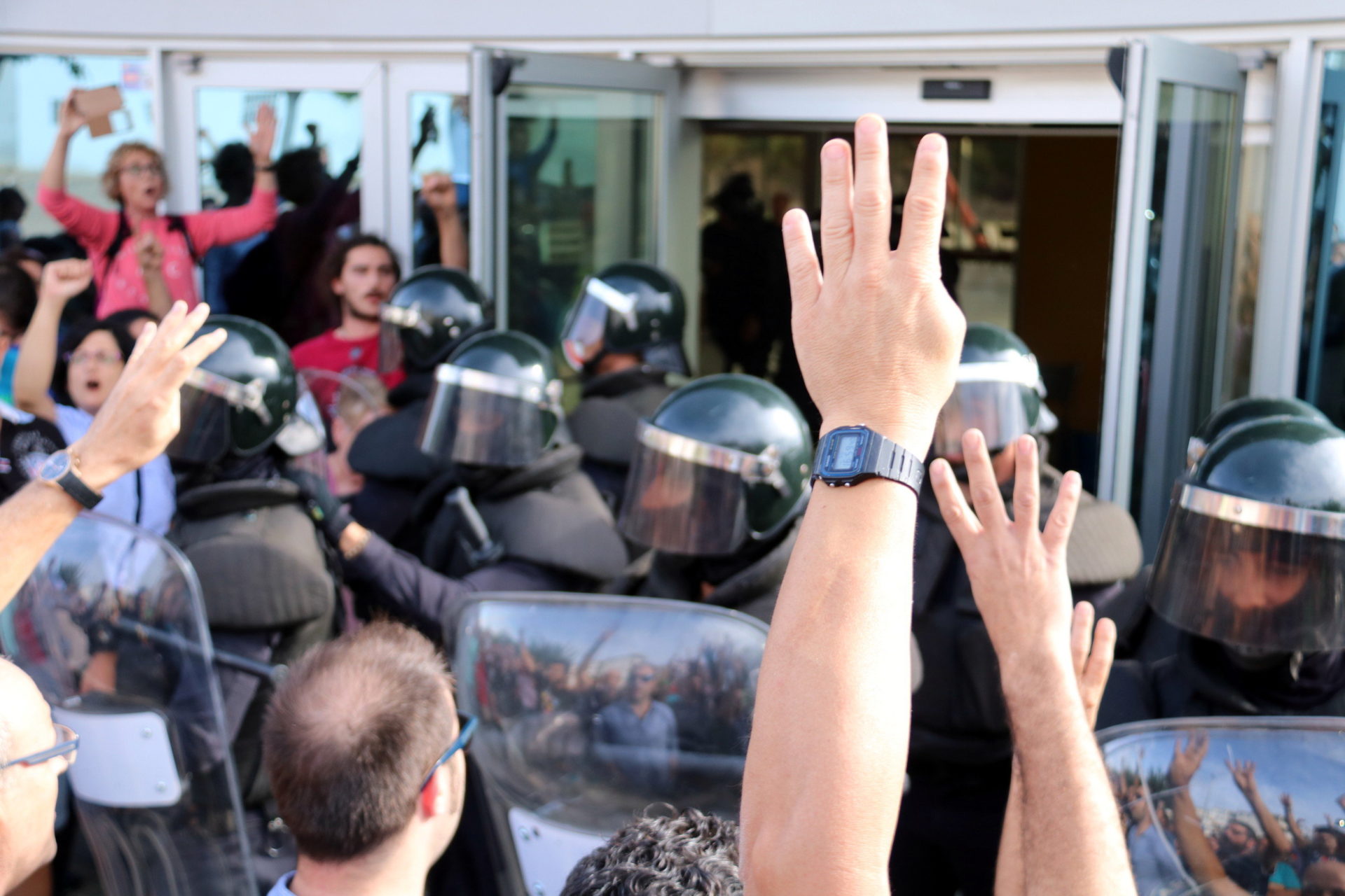 Pla detall de mans mostrant quatre dits davant dels antiavalots de la Guàrdia Civil / Anna Ferràs
