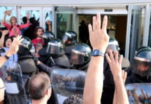 Pla detall de mans mostrant quatre dits davant dels antiavalots de la Guàrdia Civil / Anna Ferràs